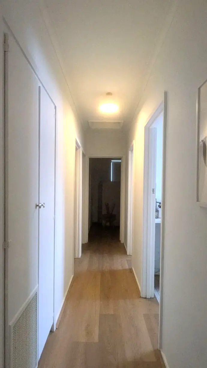 Renovated hallway with clean white paint walls, strategic lighting, and polished hybrid flooring in full Morwell home transformation.