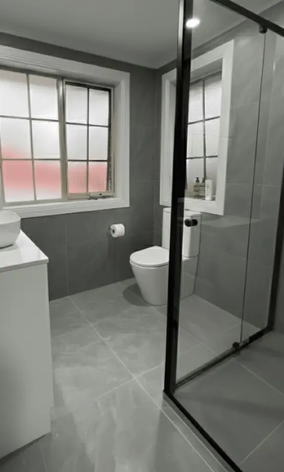 Modern bathroom with toilet and glass shower during a renovation project