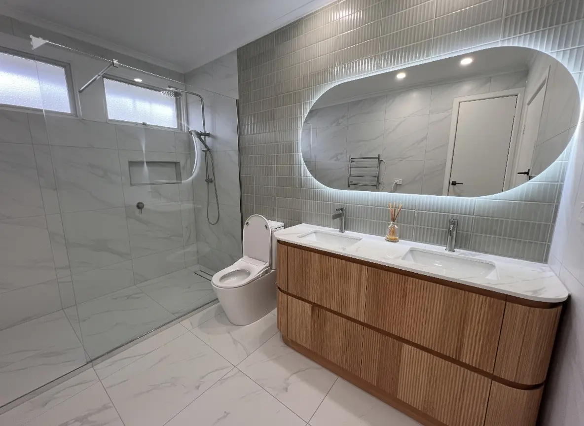 Modern bathroom design featuring wall mounted vanity and oval backlit mirror